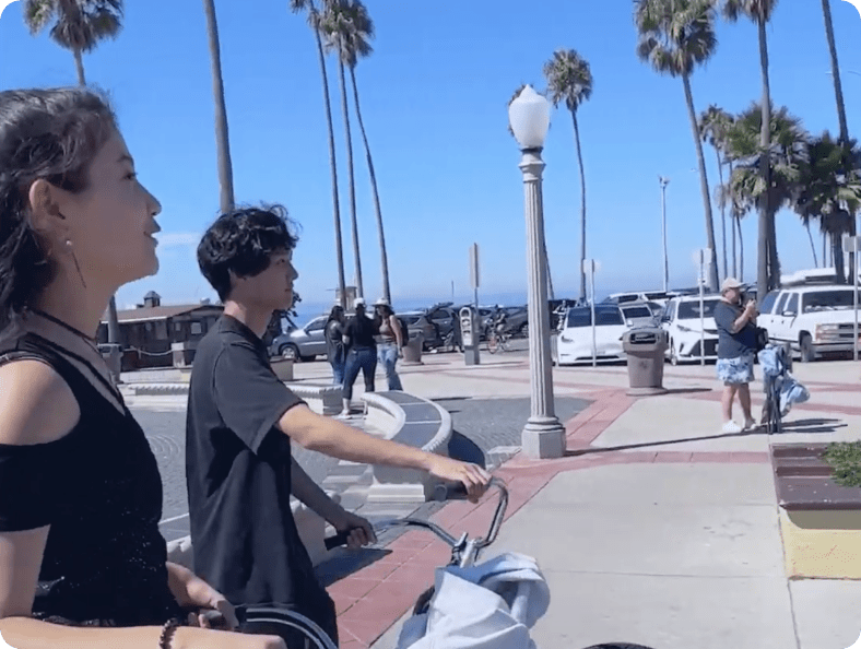 Boy and girl walking with bike on sidewalk near beach