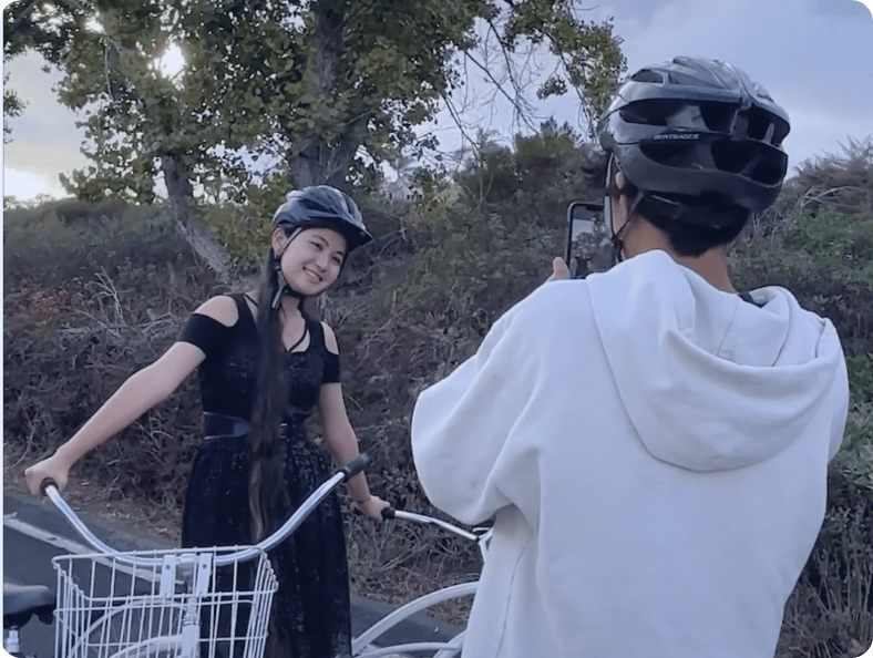 Boy taking a photo of a girl walking a bike